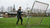 Een speler oefent met een rebounder, gericht op passing en balcontrole op een grasveld.