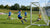 Een aluminium voetbaldoel geplaatst op een veld, omringd door spelers in training.