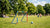Kinderen schoppen een voetbal in een kleurrijk, klein voetbaldoel op een grasveld. Veel vrolijke gezichten.