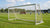 Een stevige voetbalgoal op een grasveld, omringd door spelers in actie tijdens een competitiewedstrijd.