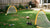Een speler plaatst een mini voetbaldoel op gras, met handdoeken en stenen voor stabiliteit zichtbaar in de omgeving.