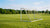 Een voetballer staat naast een inklapbaar doel in een grasveld, terwijl hij de constructie controleert.