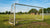 Een versleten voetbaldoel in een sportcomplex, met zichtbare roest en beschadigingen door intensief gebruik.