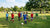 Lichte voetbaldoelen staan op een grasveld, omringd door spelende kinderen en een ouder die toekijkt.