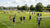 Een trainingsveld met meerdere voetbaldoelen en spelers die verschillende oefeningen doen.