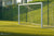 Stevig metalen voetbaldoel op kunstgrasveld met net en hekwerk.