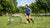 Een voetballer traint met een mini doel en een rebounder op een grasveld, gefocust op balcontrole en techniek.