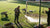 Een onderhoudsmonteur controleert het net van een groot voetbaldoel op een zonnige trainingsdag.