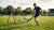 Een speler oefent met een rebounder op een harde ondergrond, geconcentreerd en in een sportieve houding.