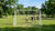 Verplaatsbare voetbaldoelen staan op een veld, een speler controleert de stabiliteit terwijl het winderig is.
