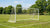 Een duurzaam voetbaldoel met coating, omringd door gras en een helderblauwe lucht.