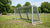 Een anti-vandalisme voetbaldoel in een park, omringd door groene grasvelden en bomen. Kinderen spelen in de achtergrond.