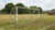 Versleten voetbaldoelen op een trainingsveld, omringd door gras en markeringen, met spelers op de achtergrond.