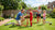 Een inklapbaar voetbaldoel in een tuin, omringd door kinderen die spelen en lachen.