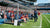 Een dugout gevuld met coaches en spelers, kijkend naar een wedstrijd op het veld.