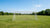 Een verroest metalen voetbaldoel in een regenachtig veld met dreigende lucht op de achtergrond.